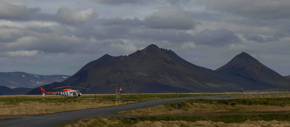 a helicopter is parked on a paved, grassy landing strip