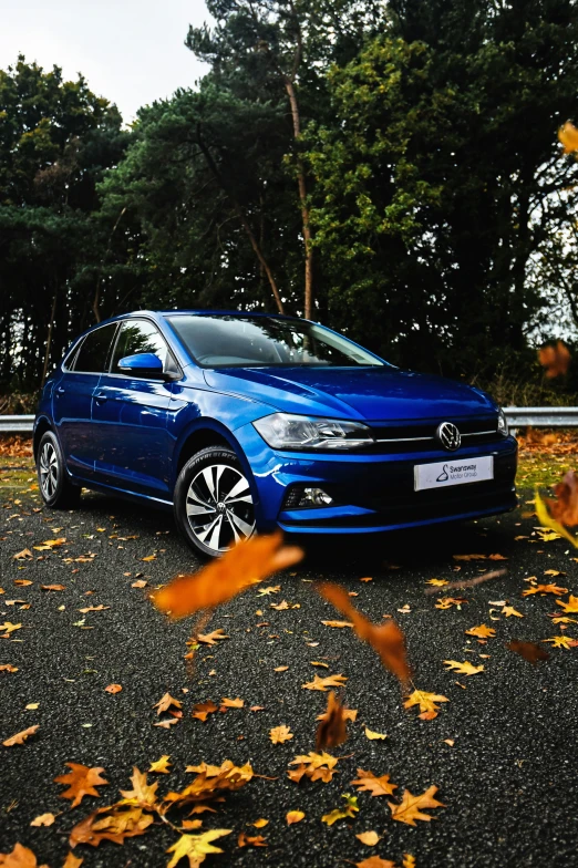 the blue car is parked along the curb in autumn