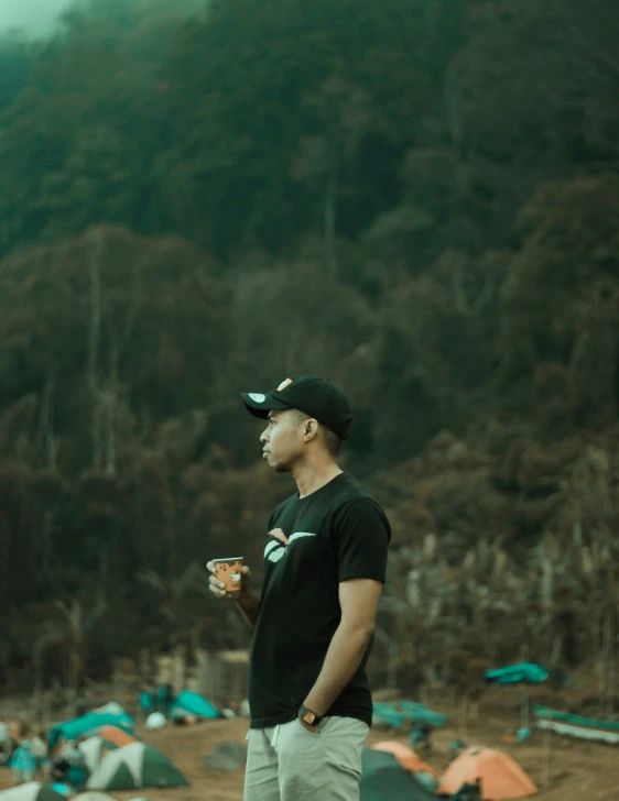 a man with a baseball cap on in front of tents