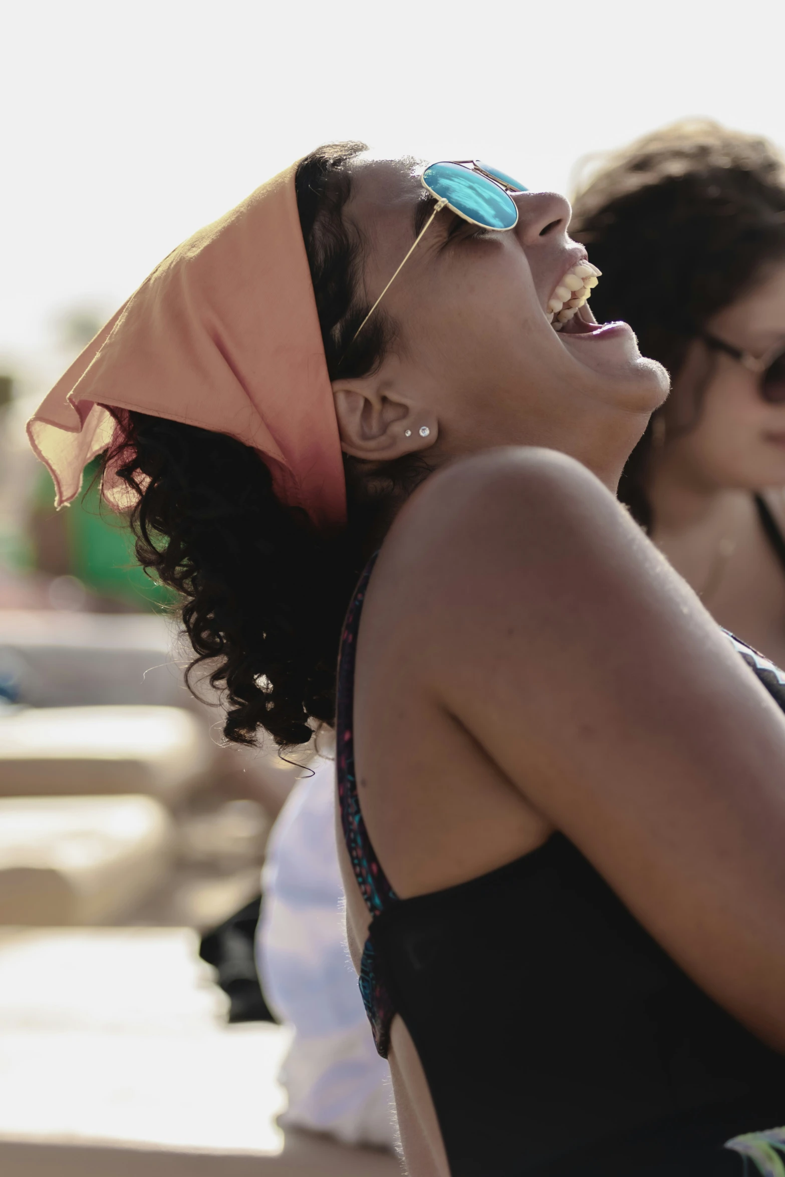 a young woman laughing and wearing sun glasses