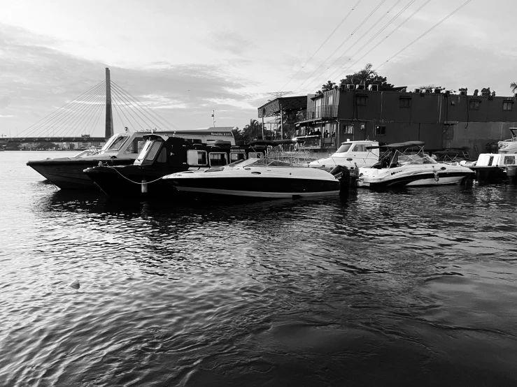 boats docked next to a bridge in black and white