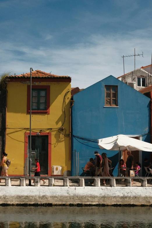 people in front of colorful buildings next to water