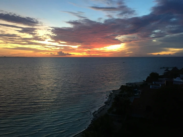 this is the sunset with clouds, buildings and water