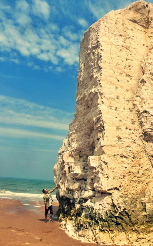 a couple stands next to the cliffs near the ocean