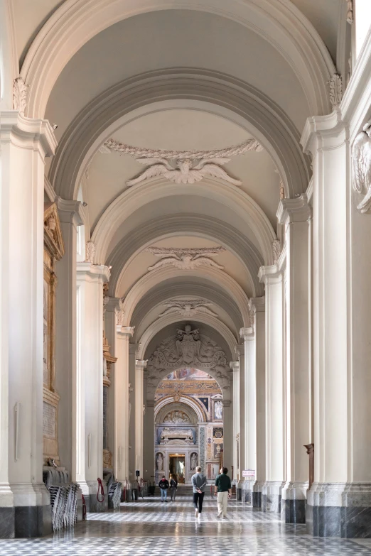 an elegant building has several arches, intricate columns and a checkerboard floor