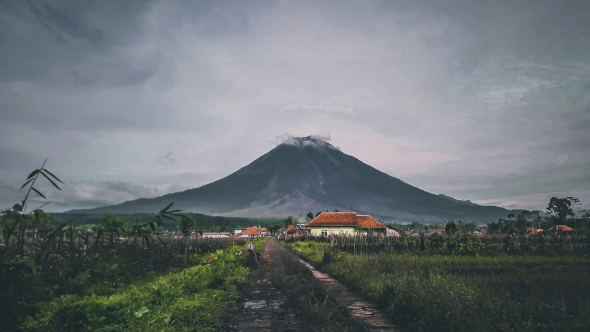 a road in front of a mountain on a cloudy day