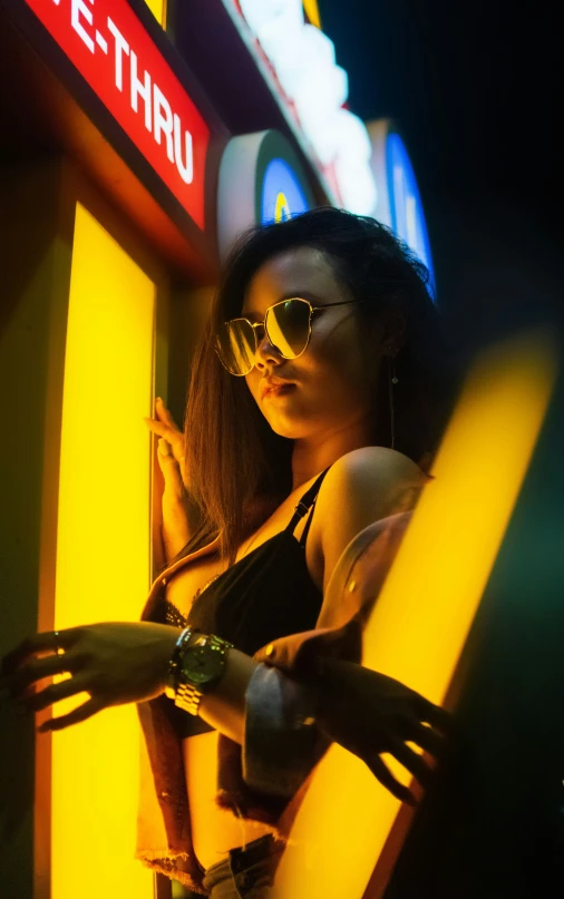 a woman wearing sunglasses posing in front of neon lights