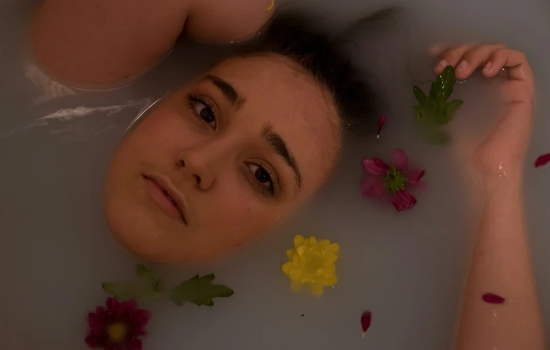 the girl is taking a bath with flower petals