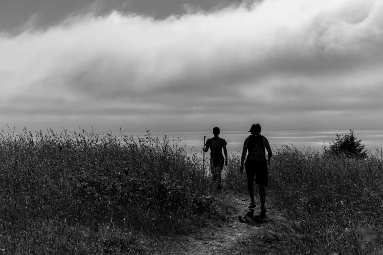 two people are walking up a hill in the grass