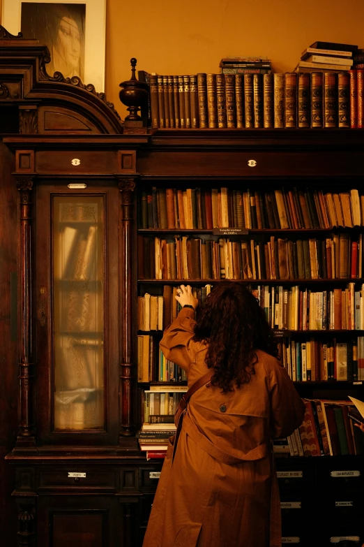 a woman standing by a bookcase with many books