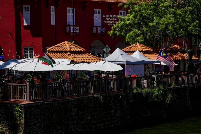 many large umbrellas and tables sitting next to a red building