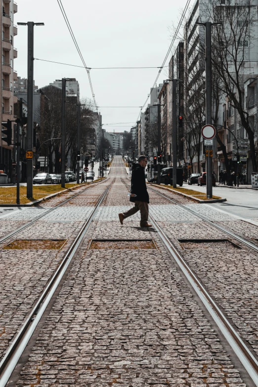 a person with a camera is crossing an empty railroad track