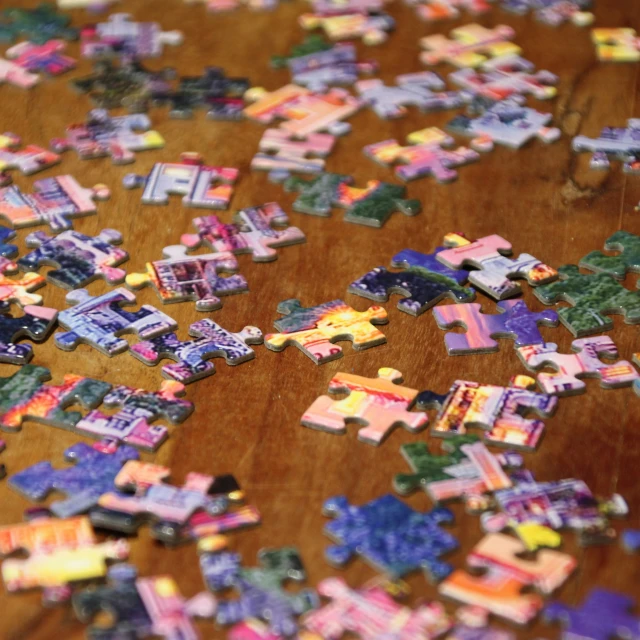 many colorful puzzles laying on a wooden table