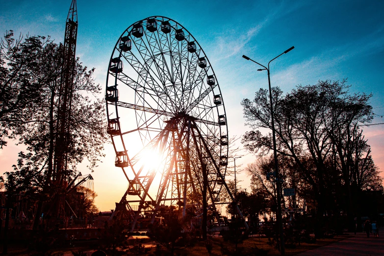 a ferris wheel is shown during sunset near trees