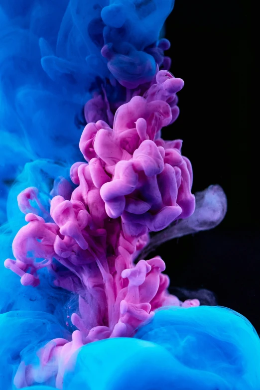 pink and blue water spewing together into a black background