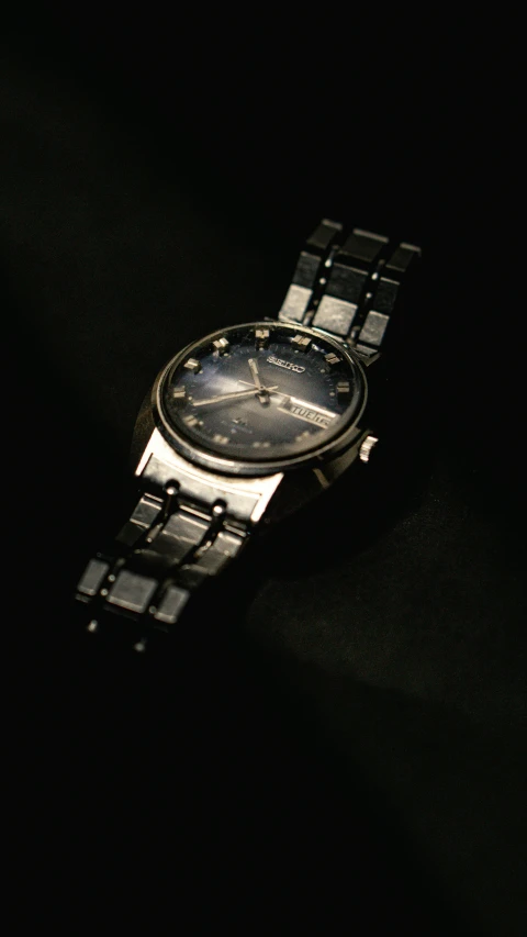 a watch with a black dial sitting in the dark