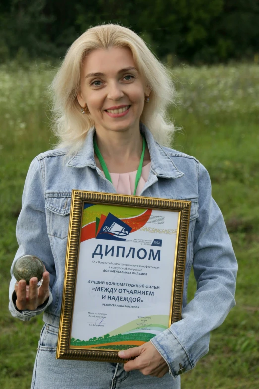 a woman holding up an award plaque for her work