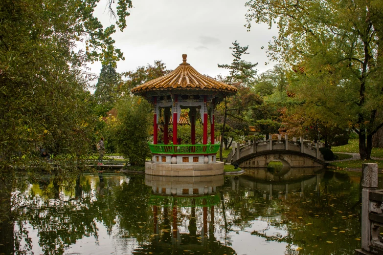 an oriental pavilion in a park near a small bridge