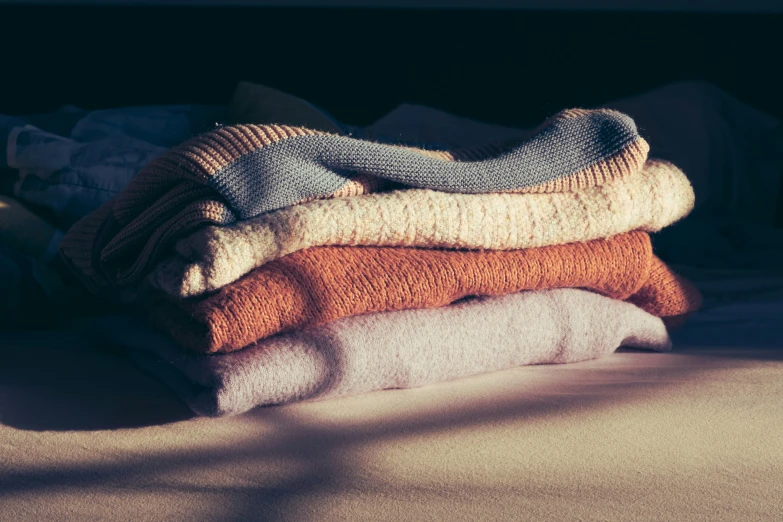 a pile of towels on a bed that are folded