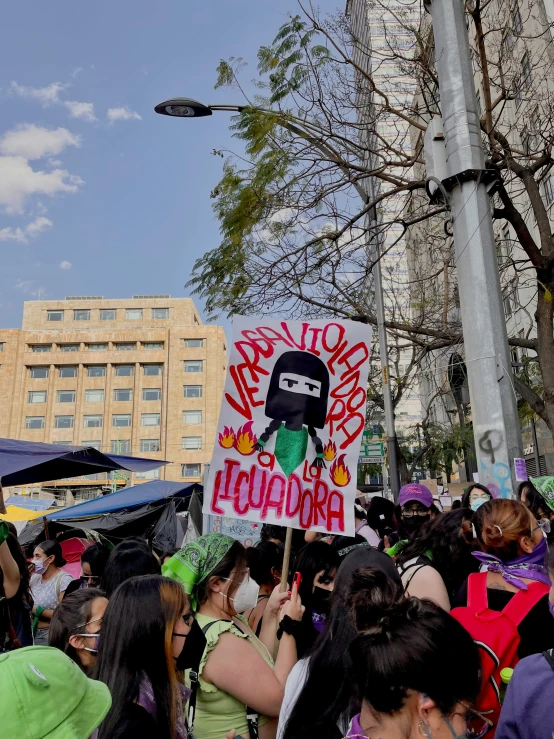 a group of people standing in a crowd holding a sign