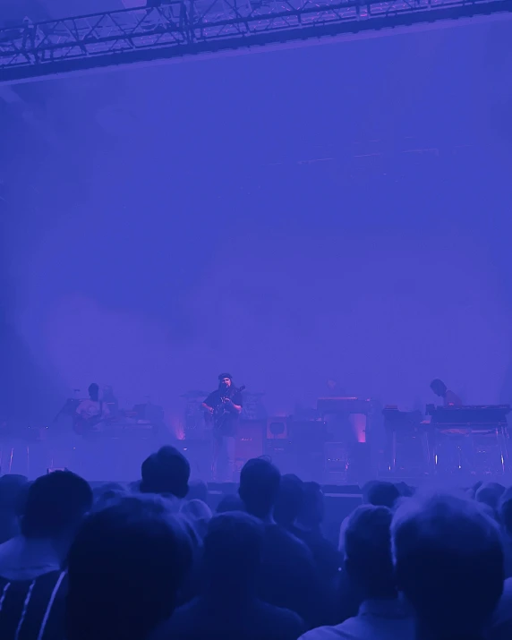 the stage is illuminated by blue lighting as a band plays on it