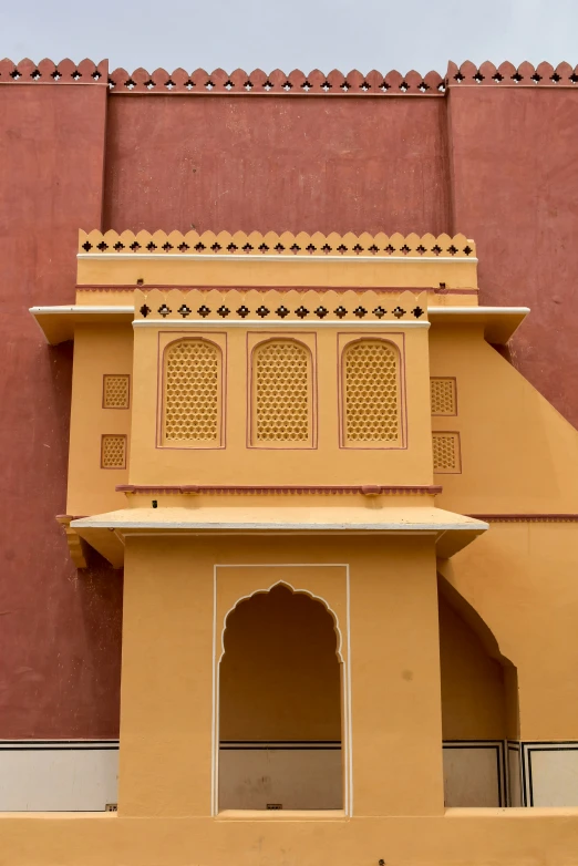 a tall yellow building with ornate architecture near a city wall