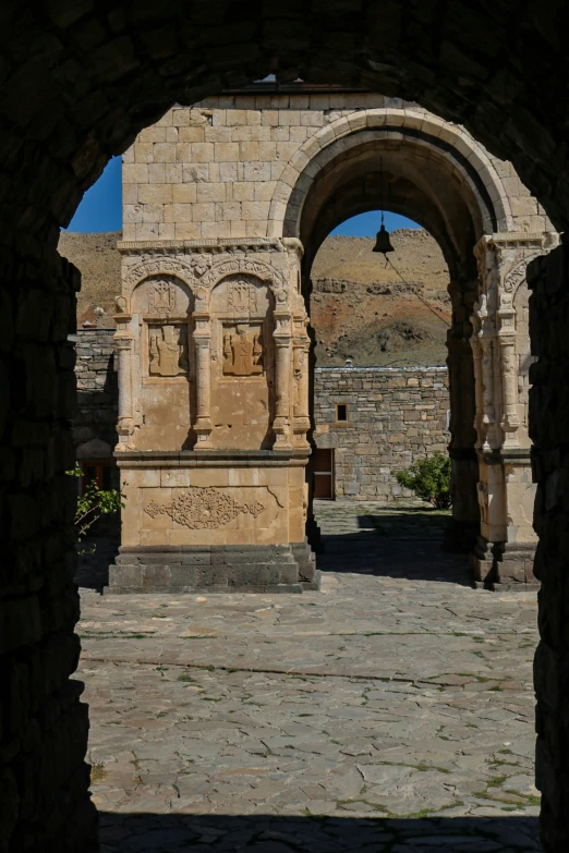 an archway on a street in front of an old wall