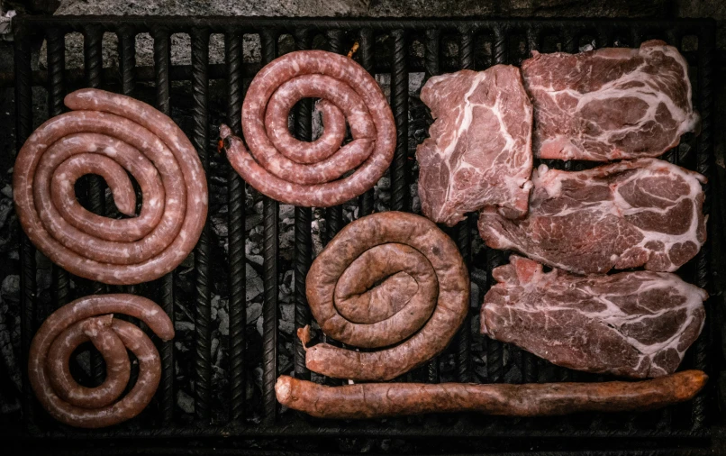 a grill covered in meat and sausages on the top of it