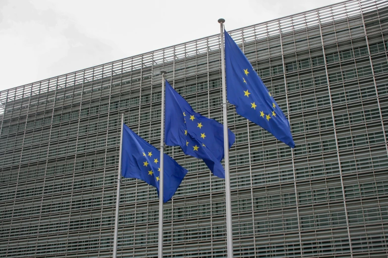 three flags flying at half mast in front of a building