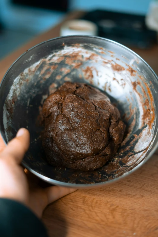 a person is holding a metal bowl with some food