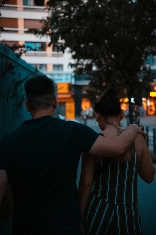 the two people walk near a street at night