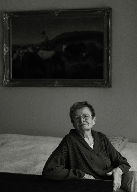 a woman sitting on a bed next to a painting