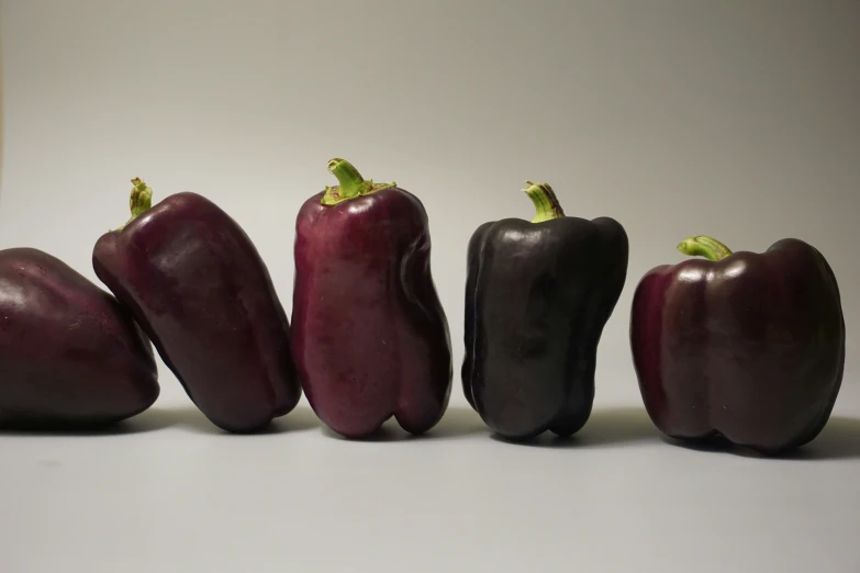 a group of five red peppers in a row