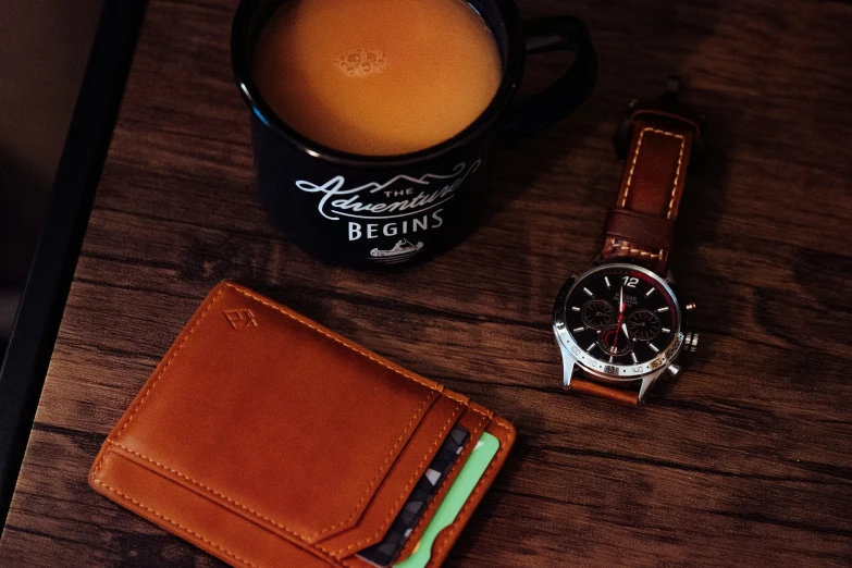 a brown wrist watch sitting next to a leather wallet