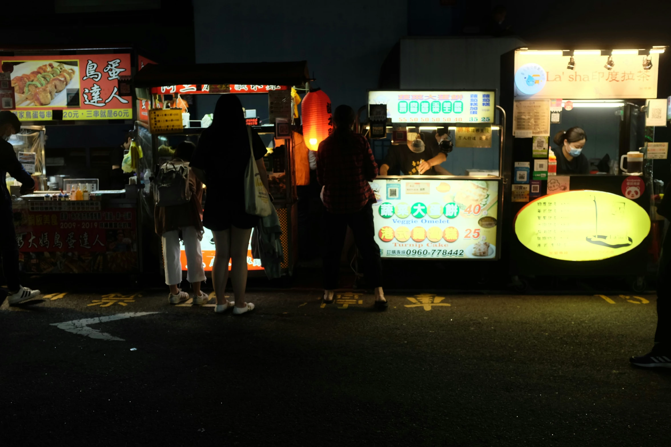 a group of people are standing at an outdoor food stand