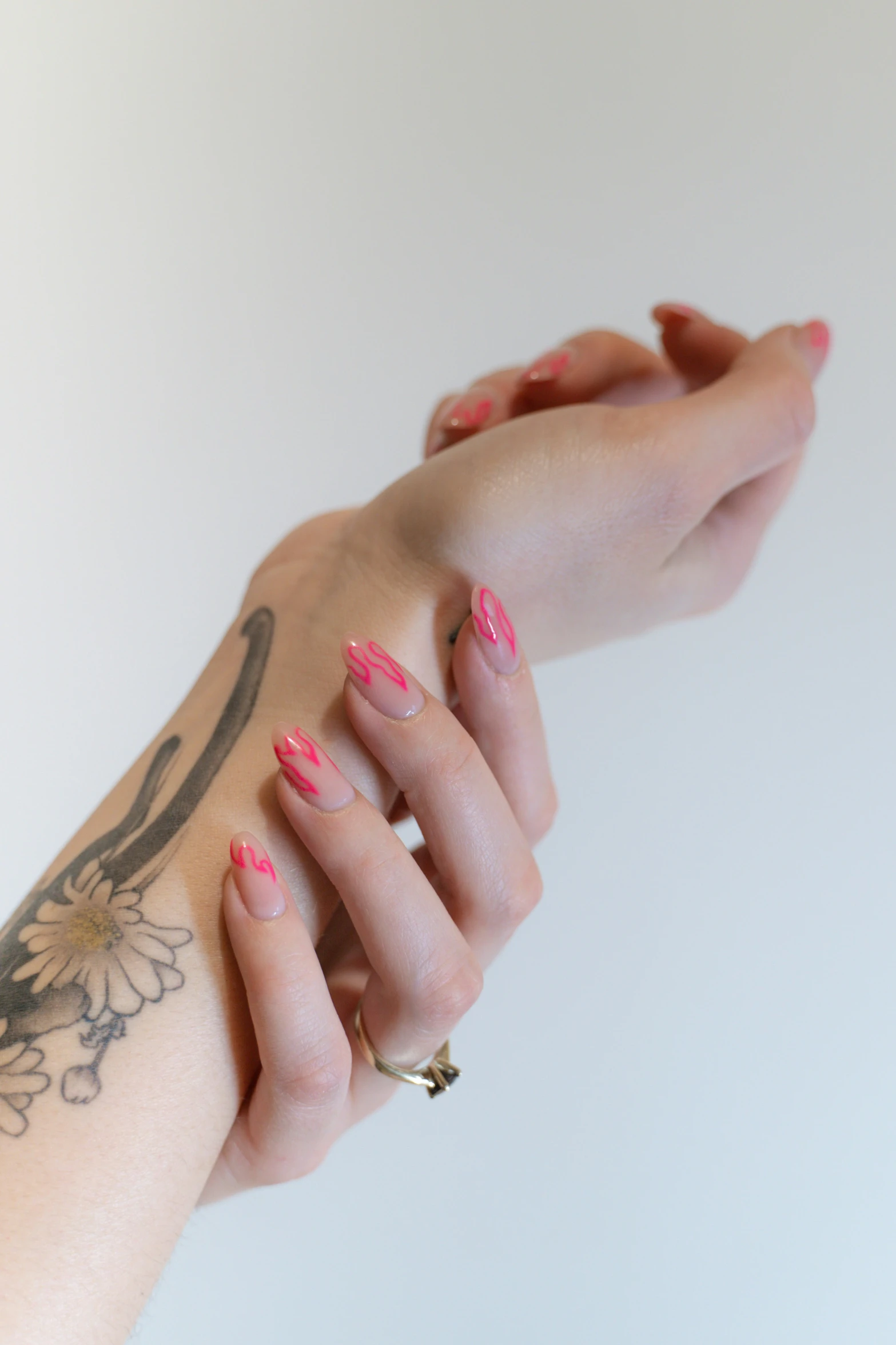 the arm of a woman with red and pink nails on her wrist