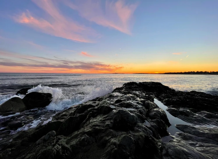 a sunset view over the ocean and some rocks