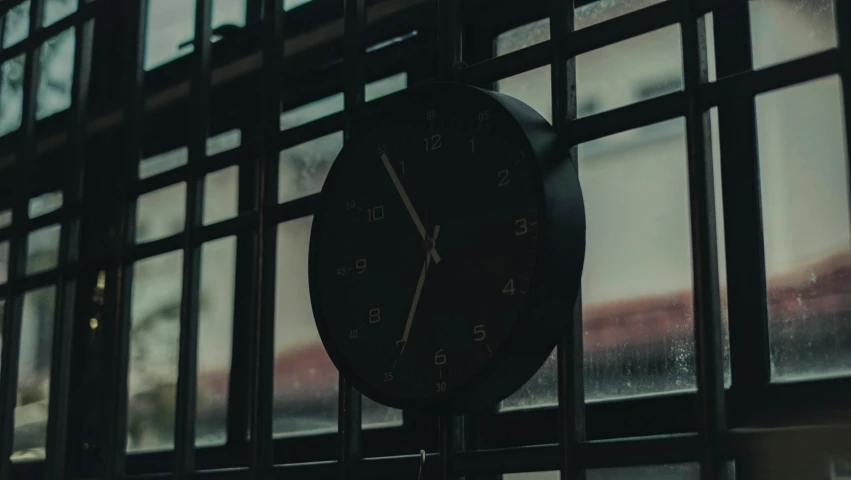 a clock with roman numerals is next to a window
