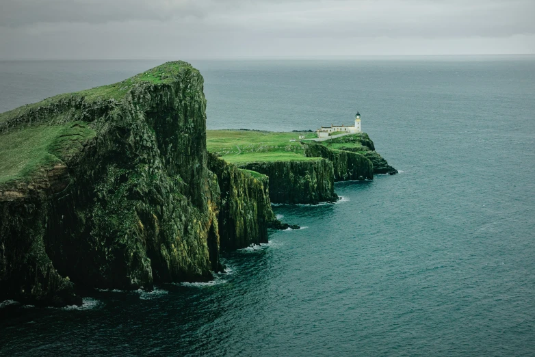 two green cliffs with a lighthouse next to the ocean