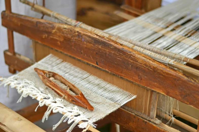 an old weaving loom with someone sewing soing on it