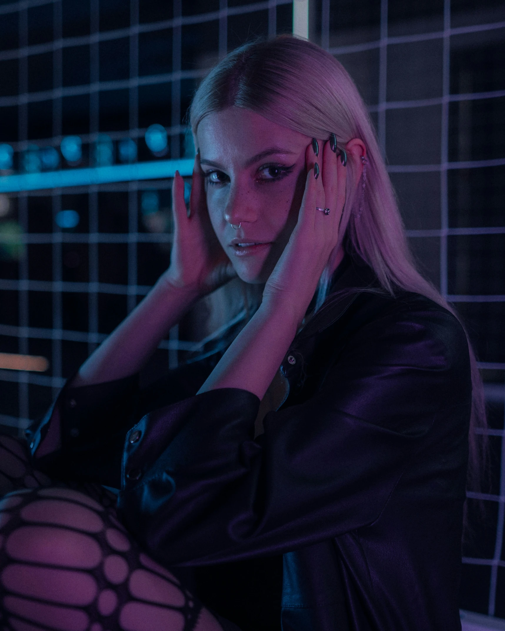 a girl sitting in front of a bathroom mirror wearing purple lipstick and black jacket