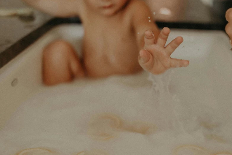 a baby sitting on a tub that is filled with water