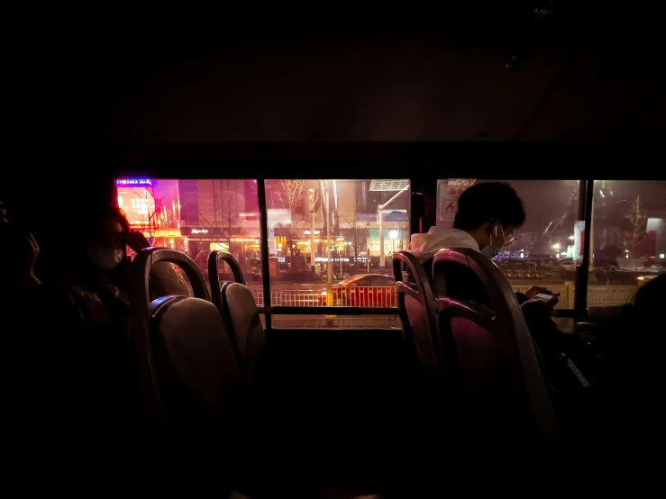 a man sits alone while looking out of a bus window