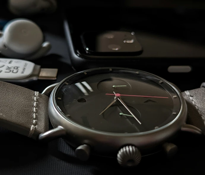 a silver watch with an empty case and keys in the background