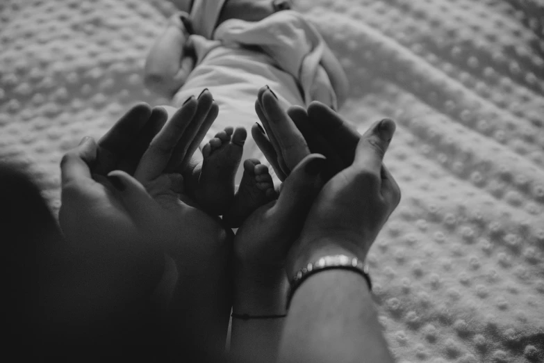 a couple of hands hold a baby on the bed