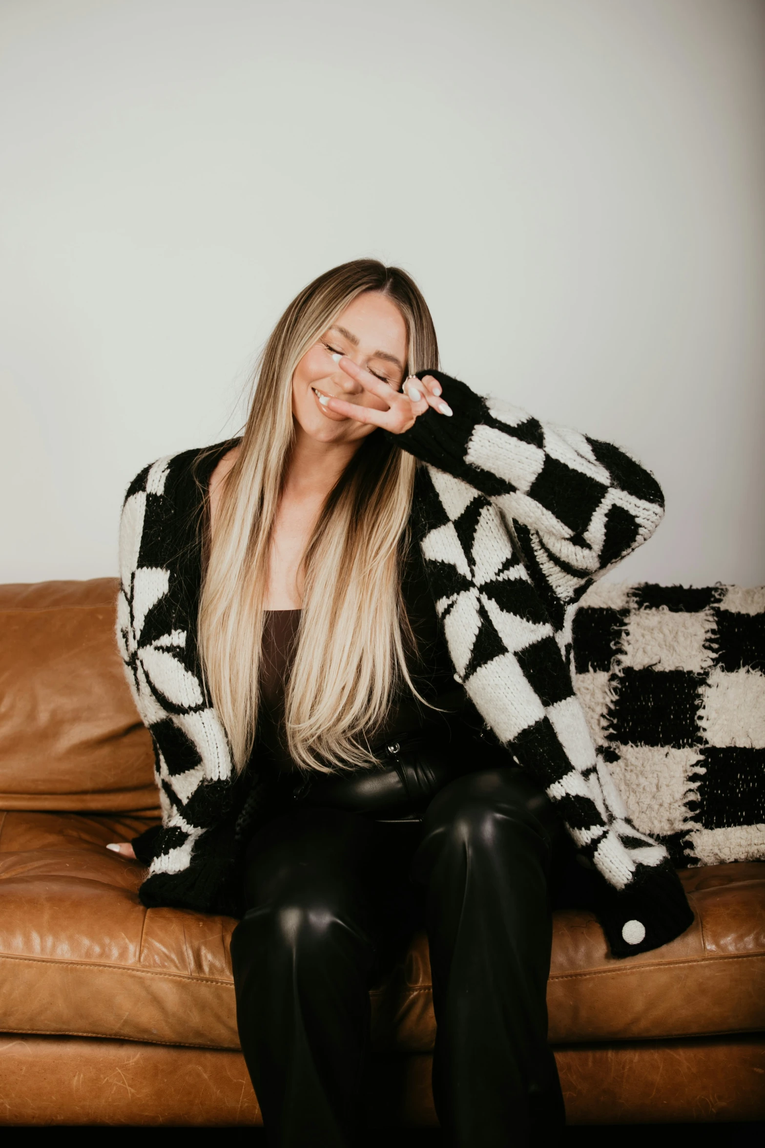 the blonde woman sits on a leather couch posing for a picture