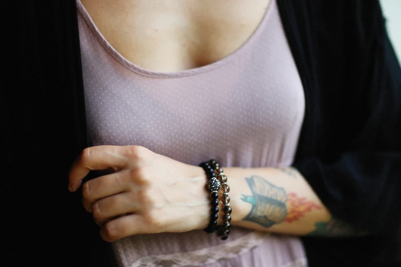 a woman with a tattooed arm wearing a celet and a ring