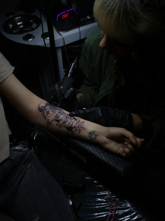 a young man is getting a tattoo on his arm