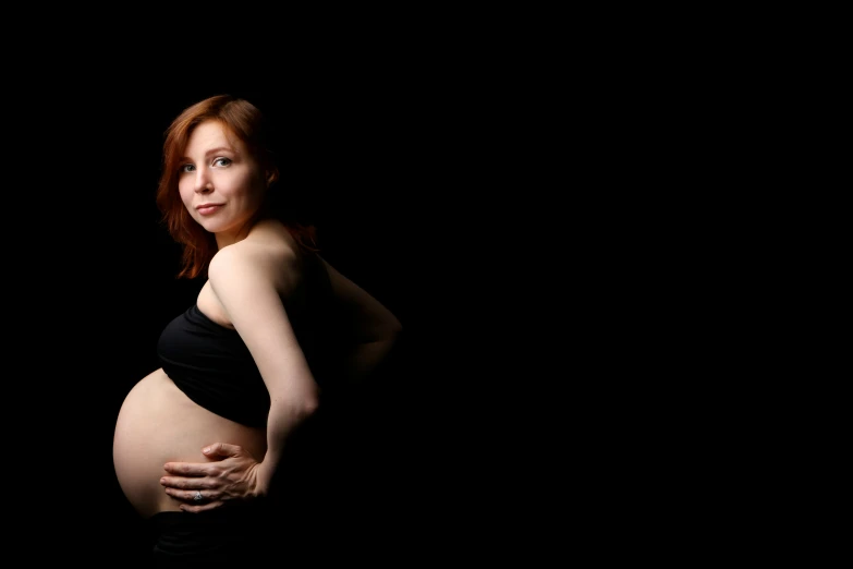 a pregnant woman in a black top standing
