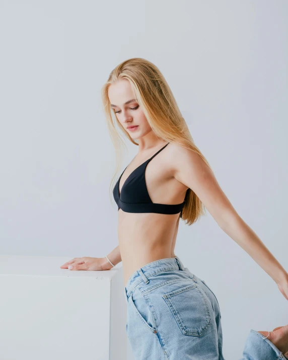 a beautiful woman standing in a black  top and jeans